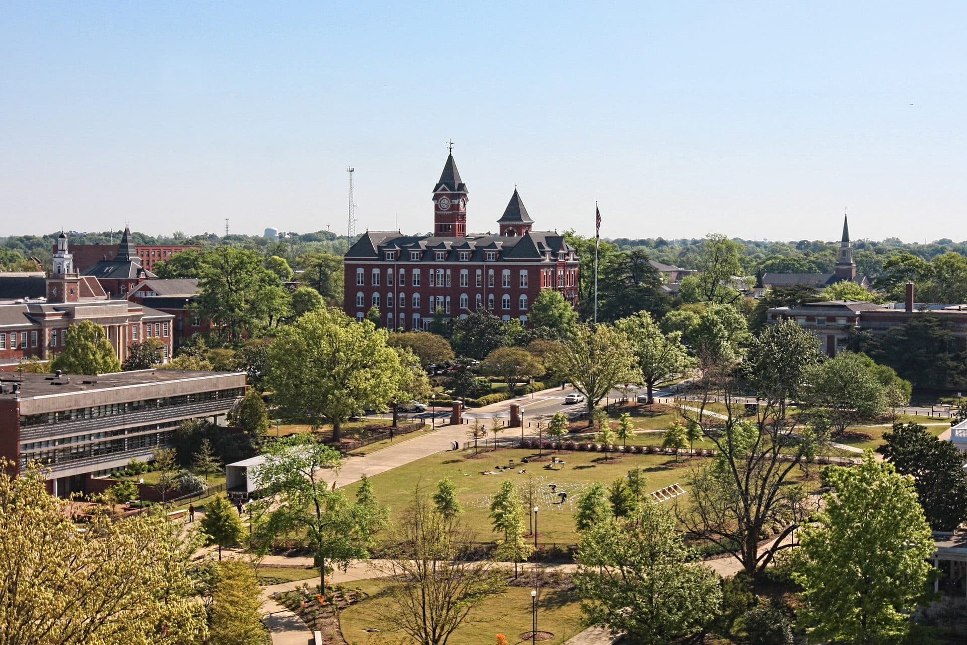 A leafy view over the Auburn University campus, with the red-brick towers of Samford Hall rising above the trees