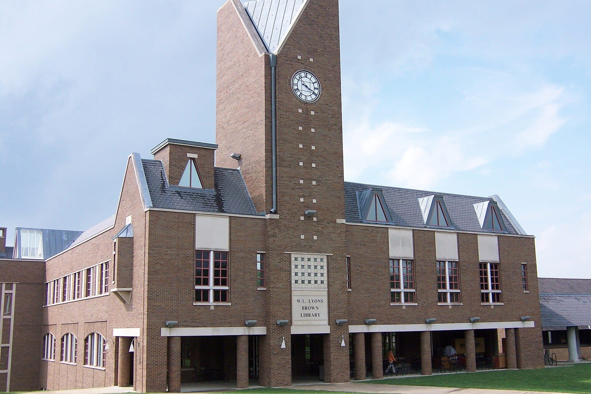 Bellarmine's red-brick W. L. Lyons Brown Library with a tall square clock tower and steep gray roofs under a blue sky