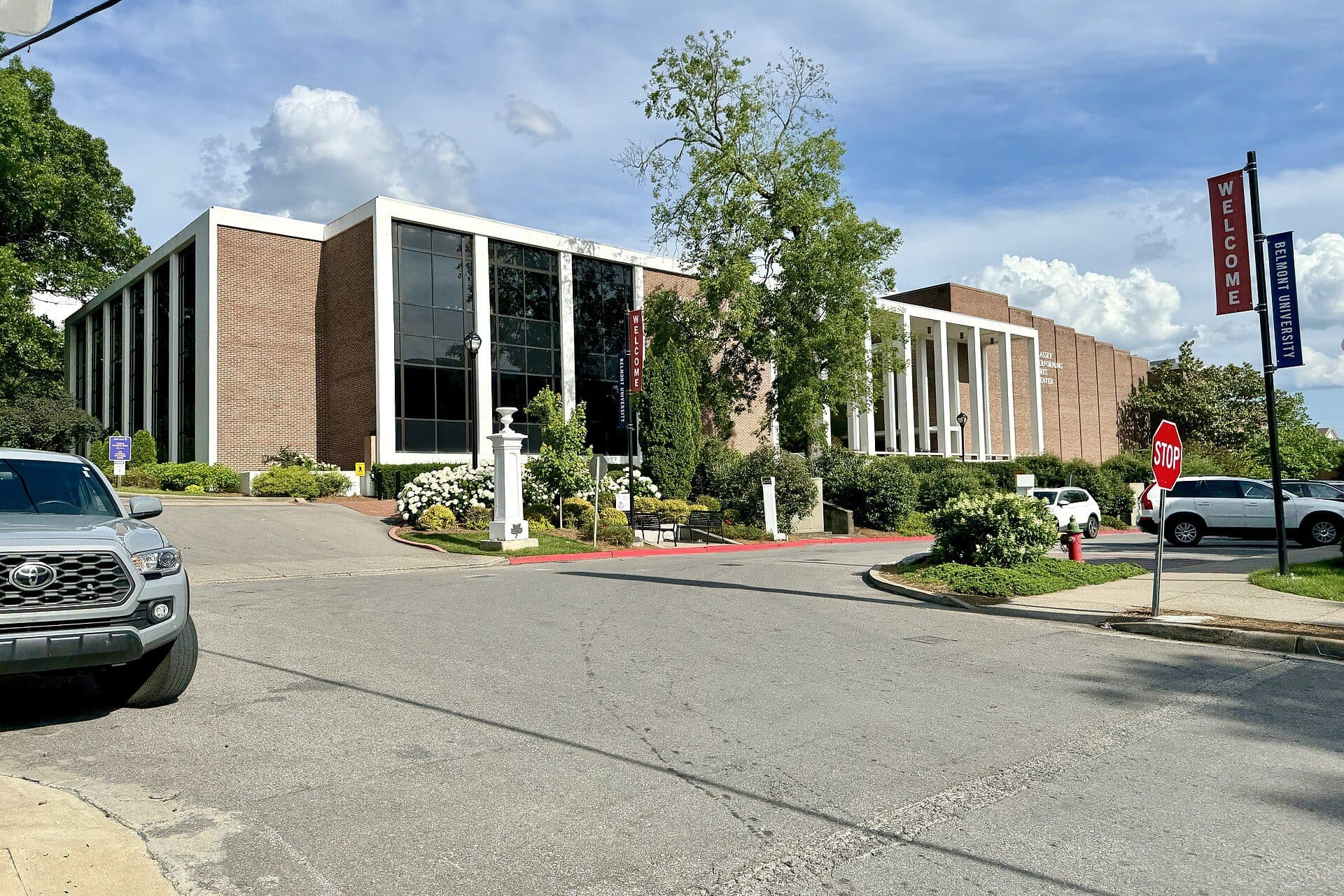 Belmont's Wilson Music Building, a brick-and-glass building with white columns, beside a campus drive with a Belmont welcome banner
