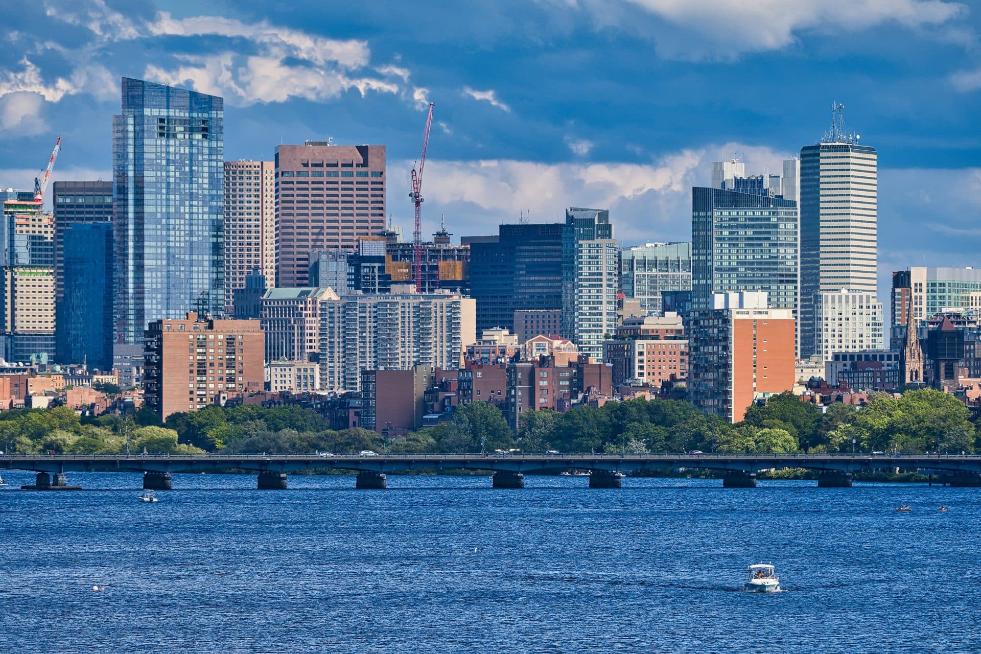 Downtown Boston's skyline across the blue Charles River on a sunny day, seen from the Boston University Bridge