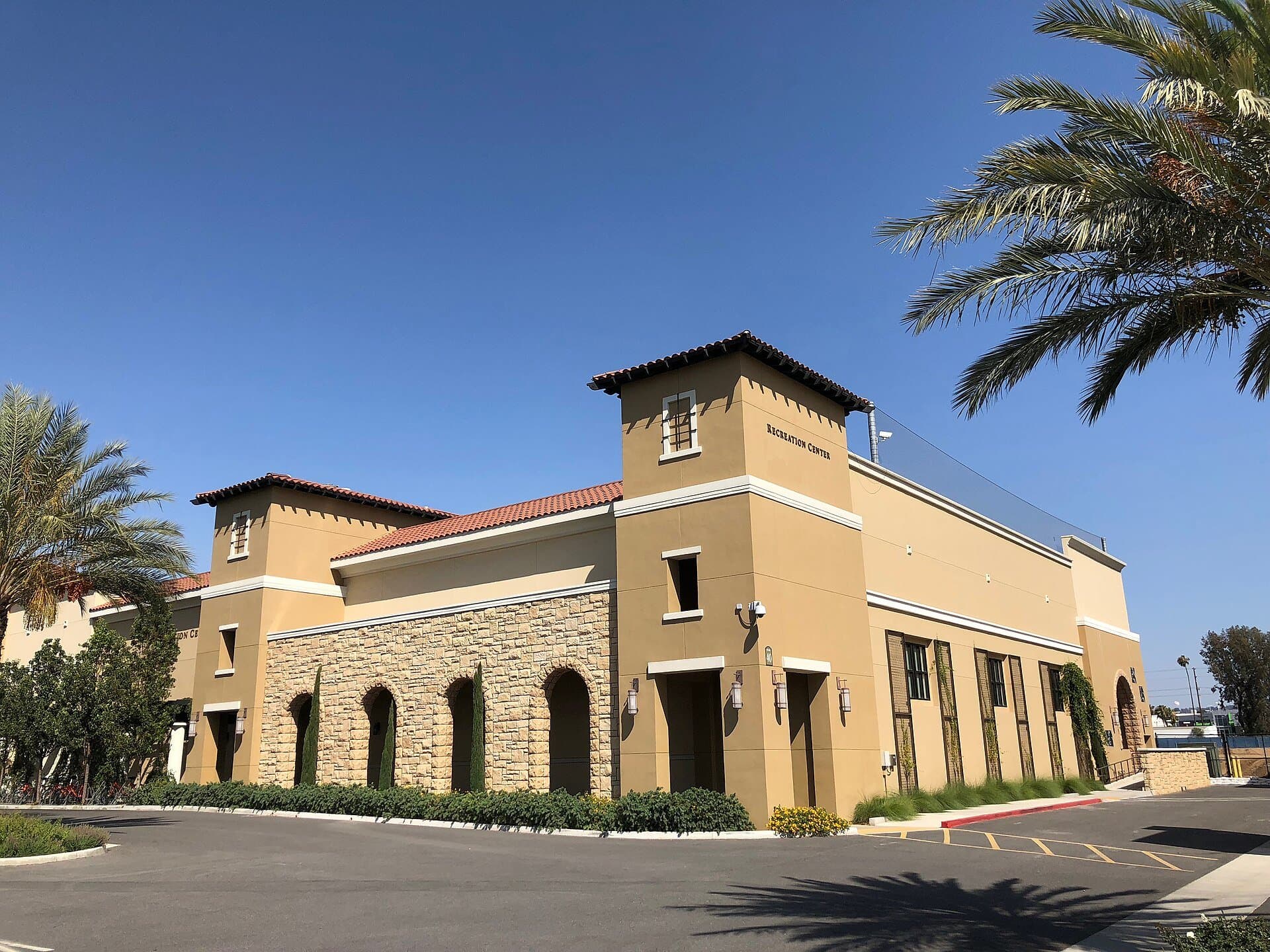 California Baptist University's Recreation Center, a tan stucco building with a red tile roof and arched windows, framed by palm trees