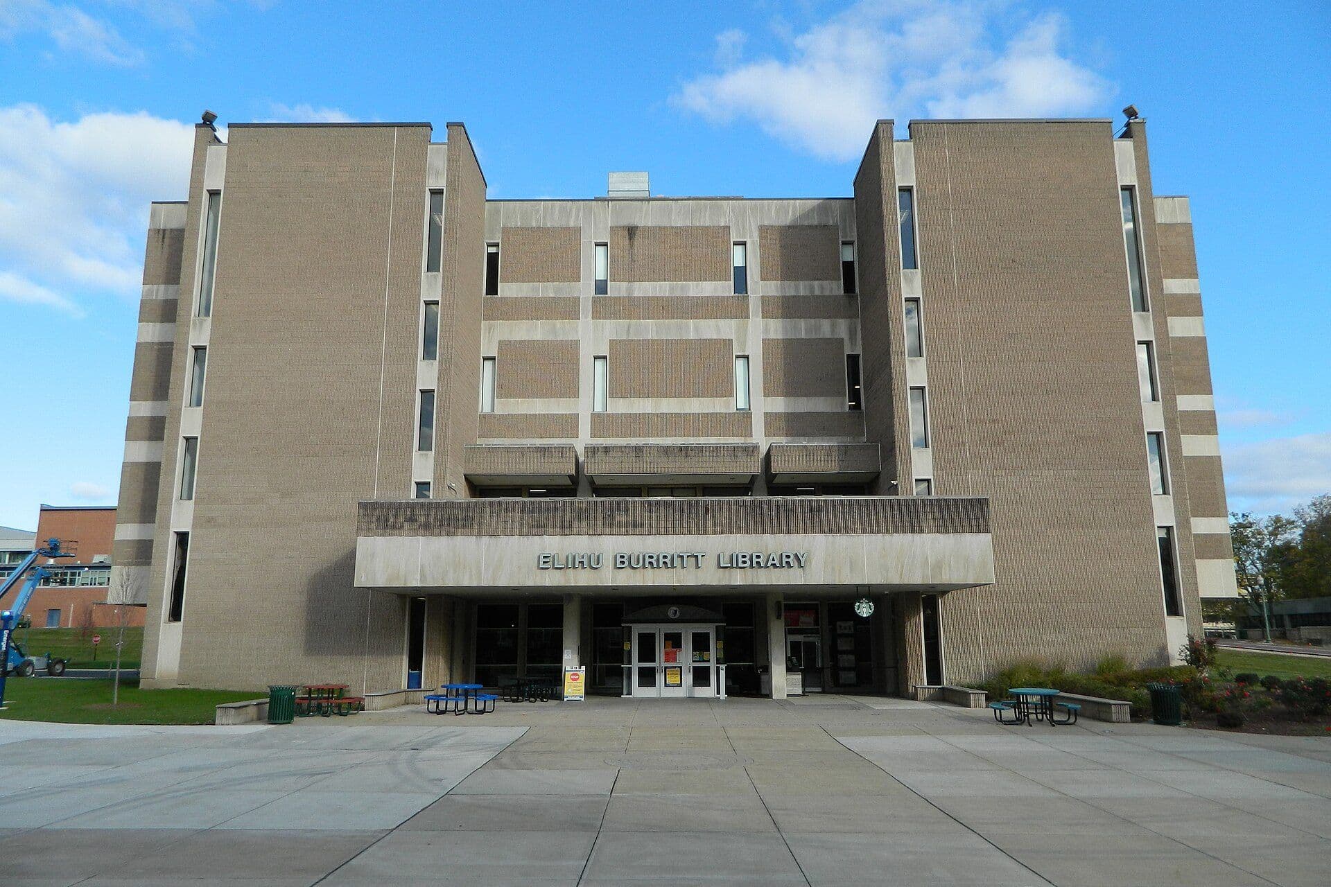 The tan concrete facade and entrance canopy of CCSU's Elihu Burritt Library across a wide plaza under a blue sky