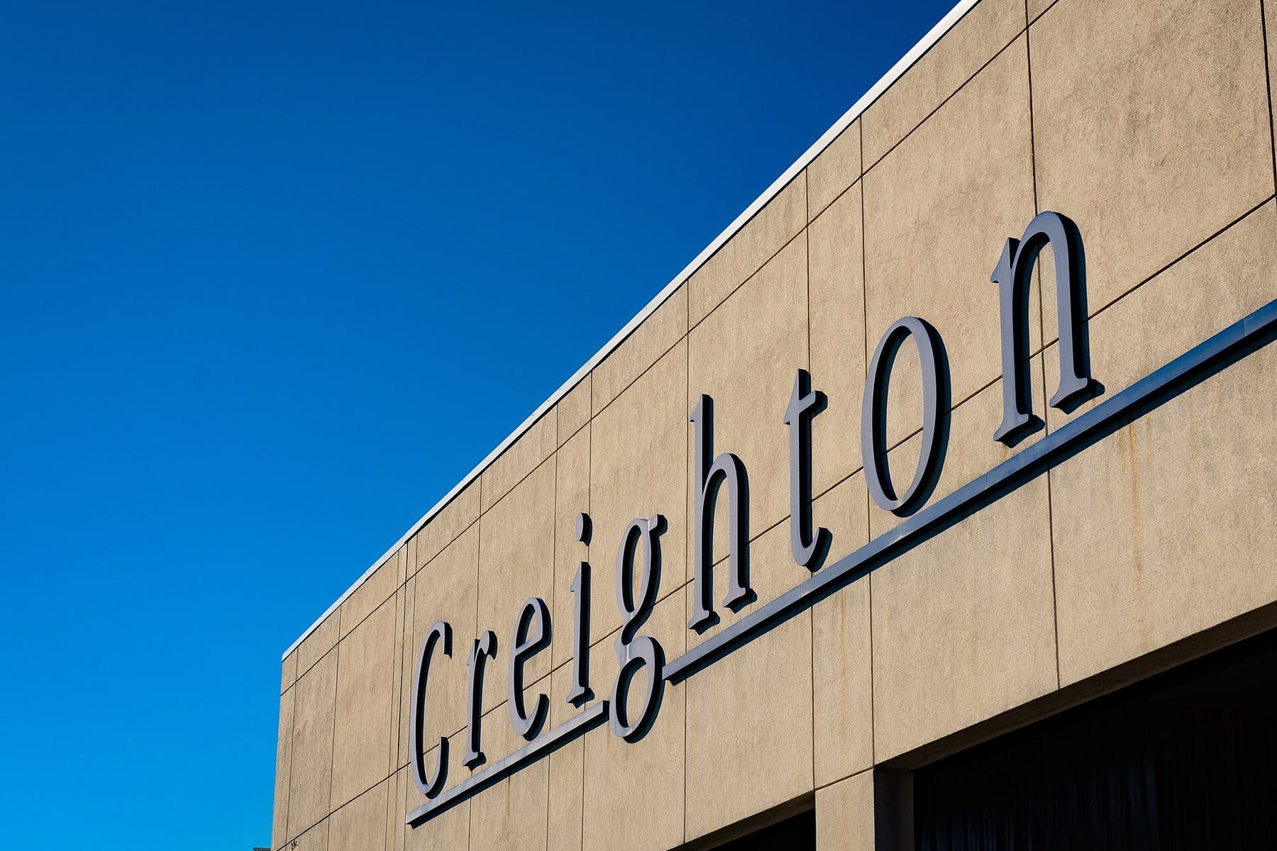 Large Creighton lettering on the Skutt Student Center at Creighton University under a deep blue sky