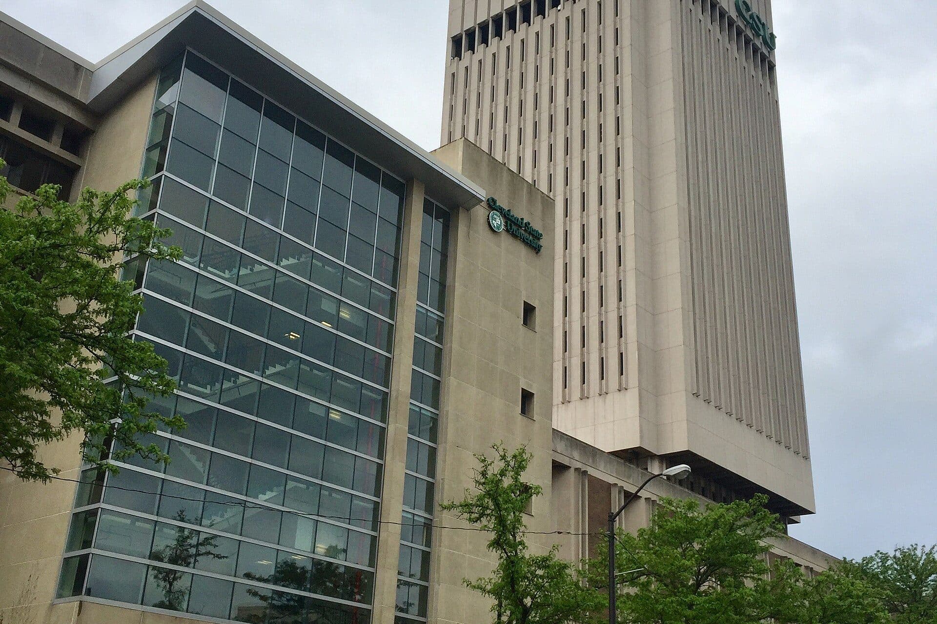 A glass-fronted Cleveland State building beside the tall concrete Rhodes Tower on CSU's downtown Cleveland campus