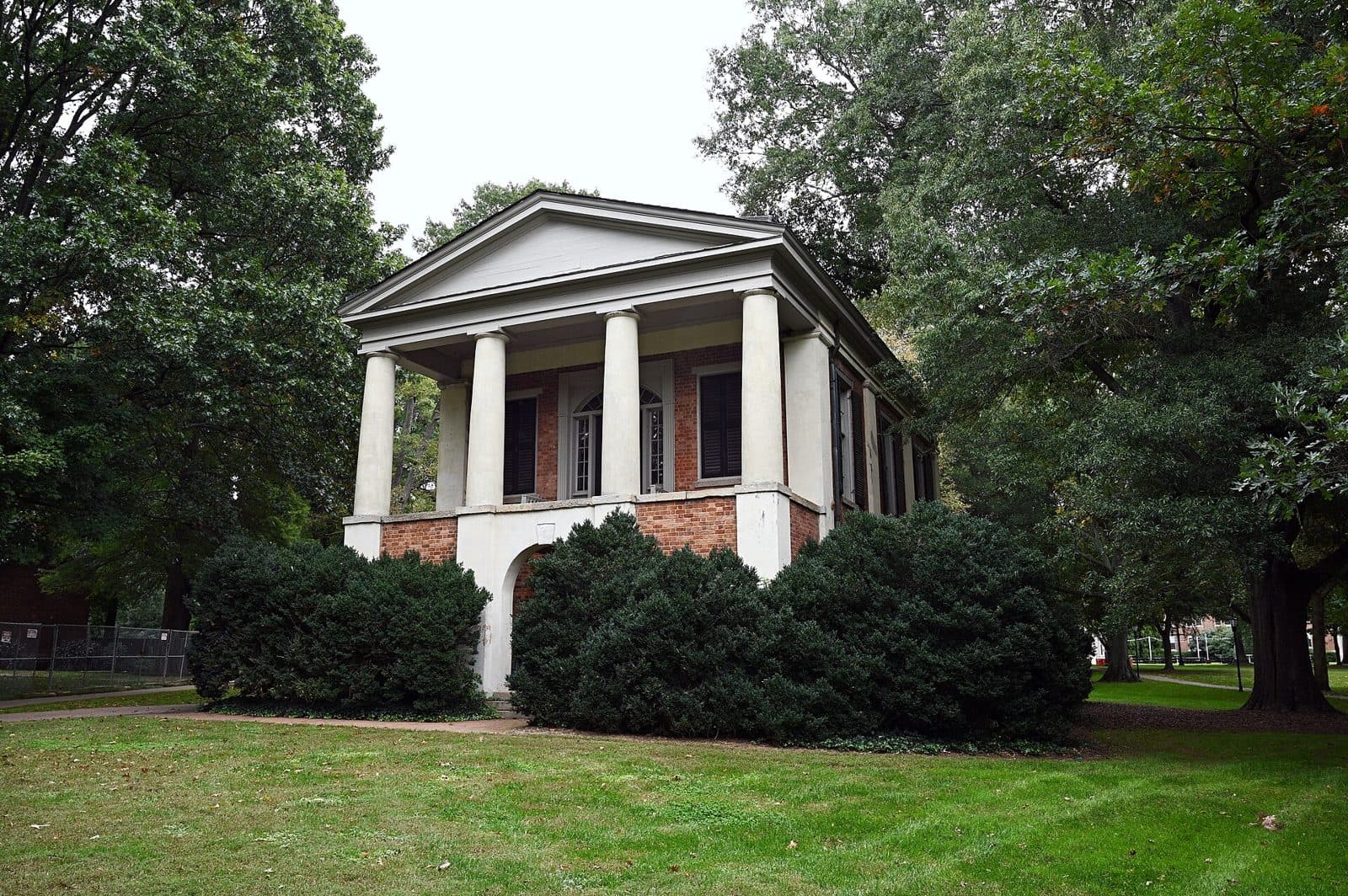 Philanthropic Hall at Davidson College, a small Greek Revival building with white columns and red brick, framed by tall trees and green lawn