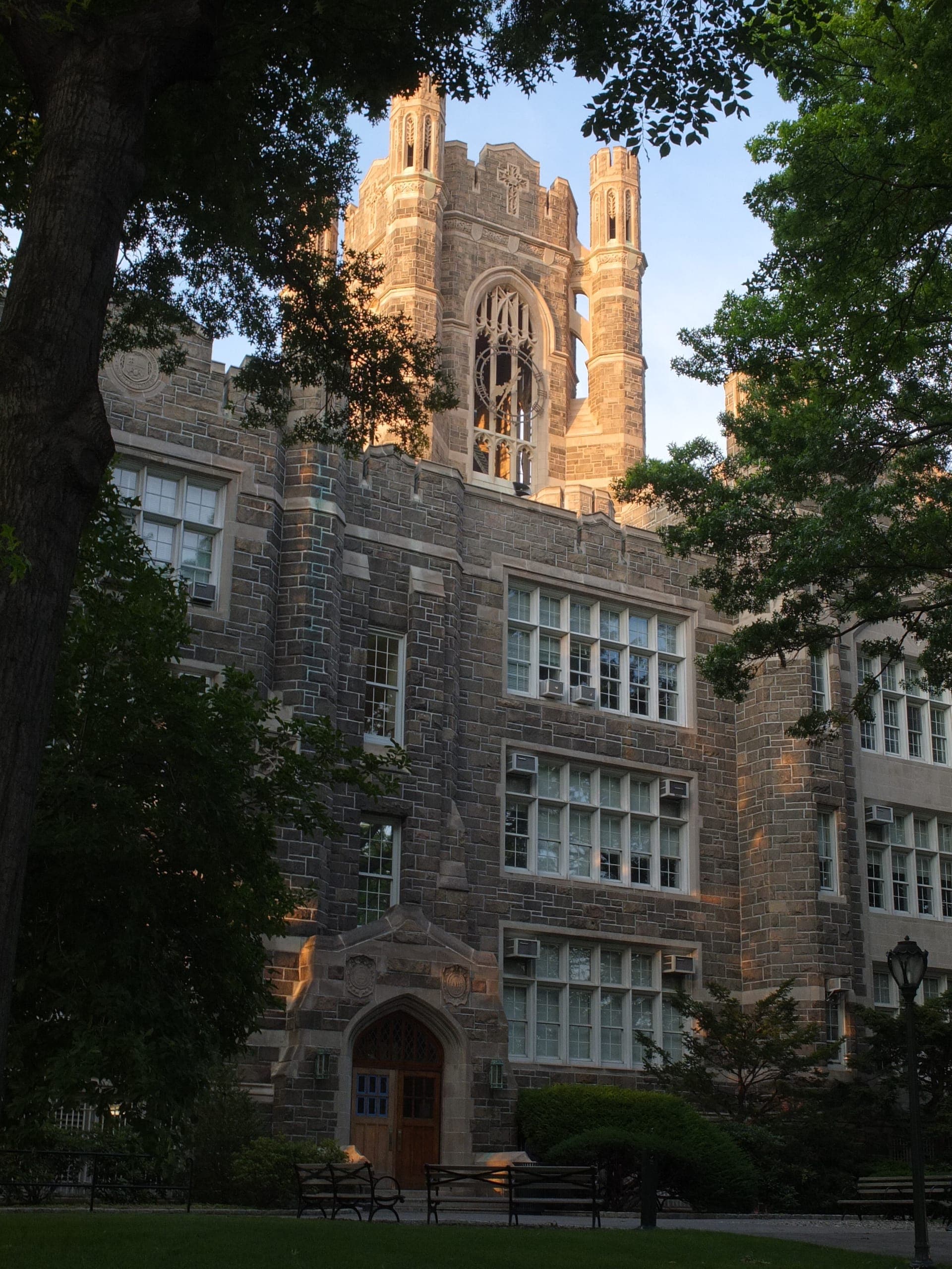 Keating Hall at Fordham's Rose Hill campus, a stone building with a tall tower, framed by leafy trees