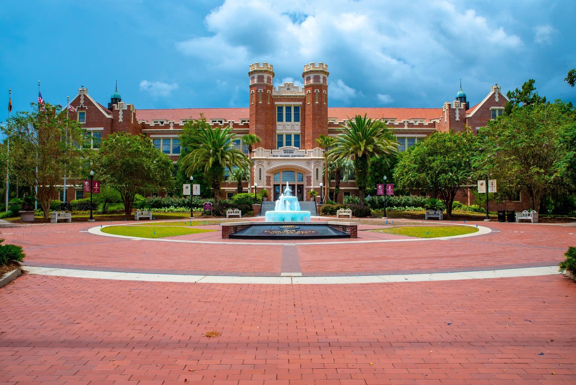 The red-brick Westcott Building with twin towers behind a fountain, palm trees and a wide brick plaza at Florida State