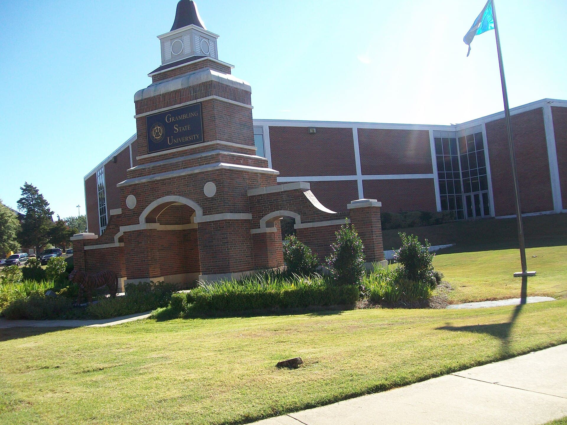 A brick entrance monument with a Grambling State University plaque and a flag flying beside it