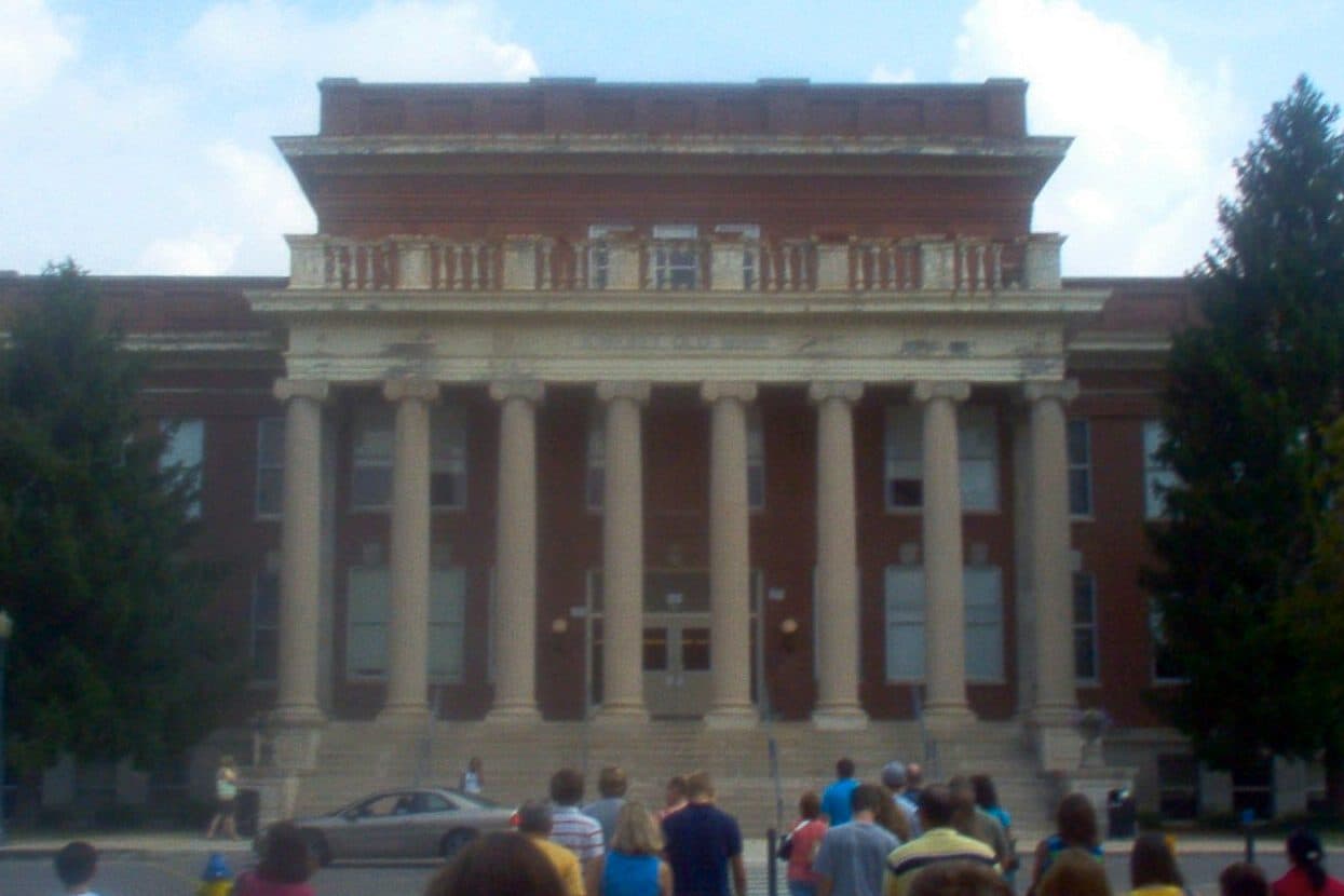 The red-brick Kirksey Old Main at MTSU, with tall white columns across its front, as a tour group gathers on the walk outside