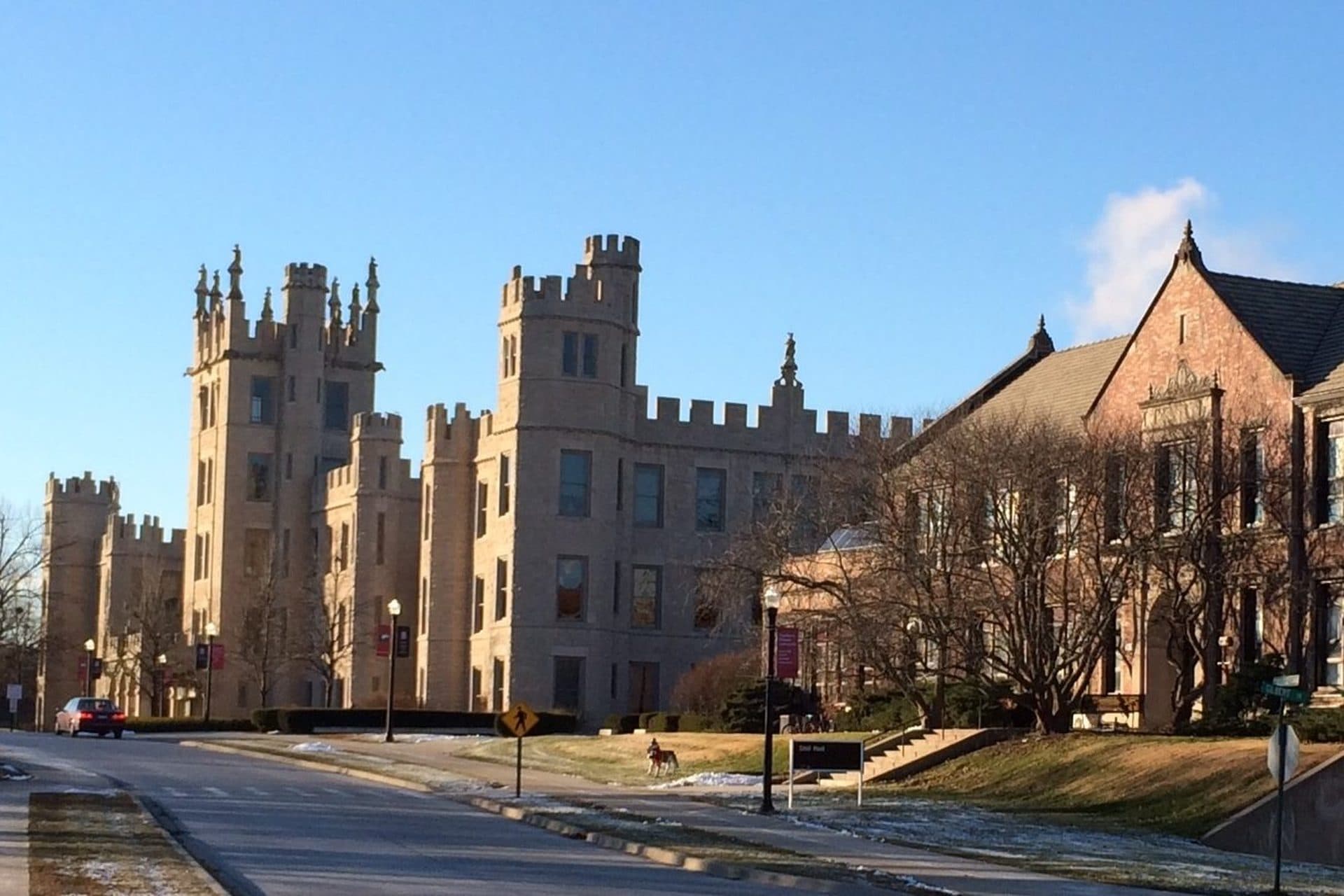 Altgeld Hall's castle-like stone towers and battlements beside Still Hall along College Avenue at NIU, under a blue sky
