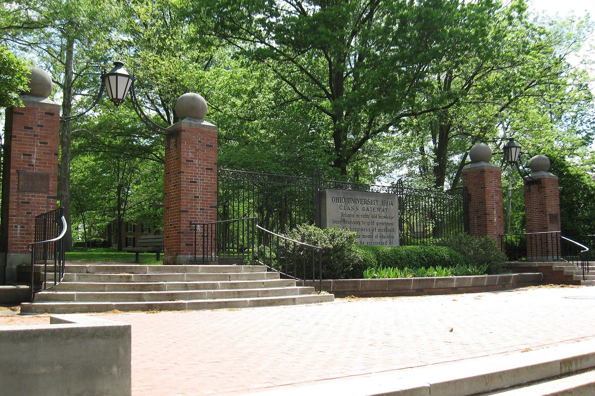 Brick pillars and an iron gate at the top of a short flight of steps leading onto Ohio University's tree-filled College Green in Athens