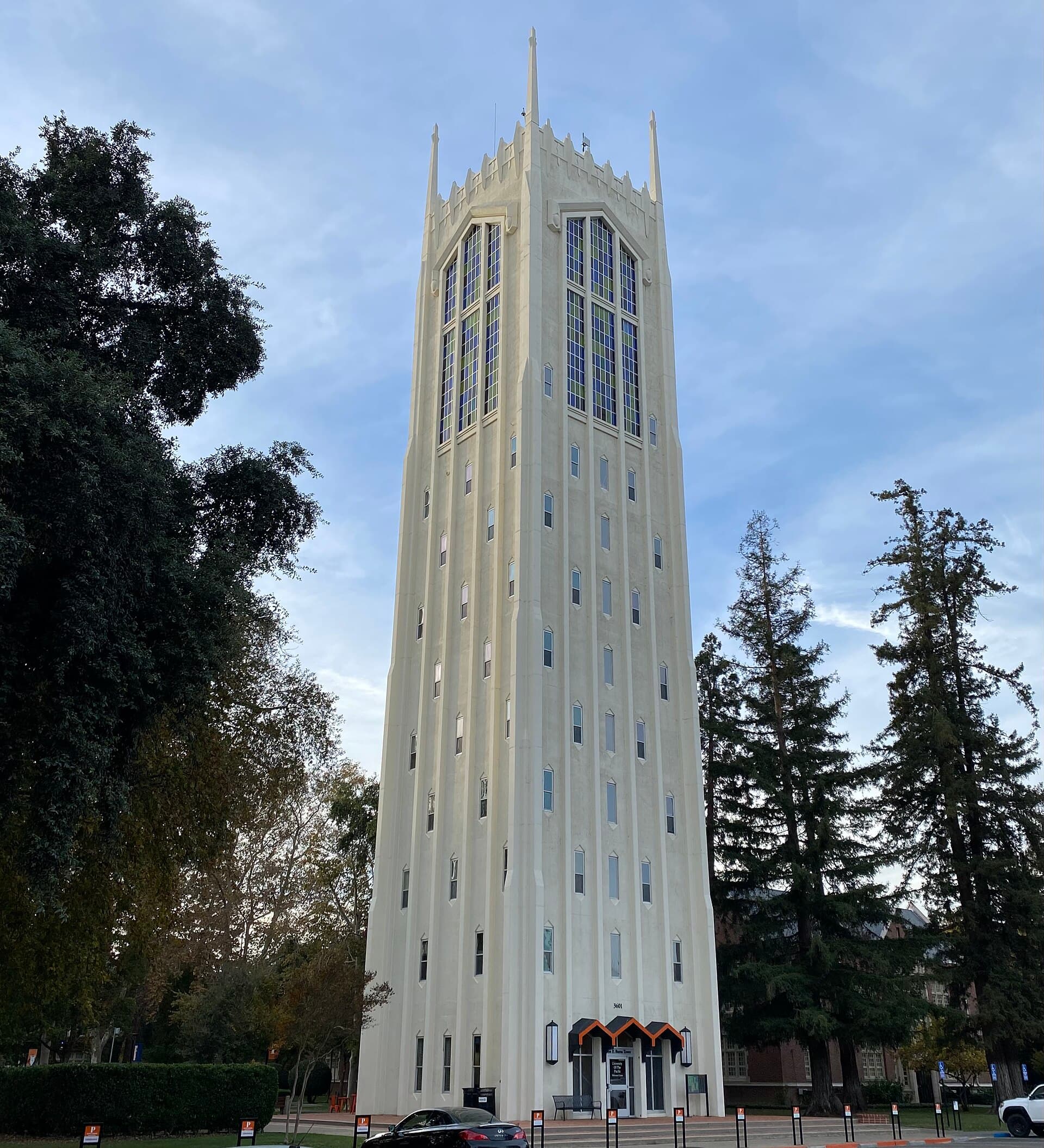 Burns Tower, a tall pale tower with arched openings near the top, rising above trees on the University of the Pacific campus