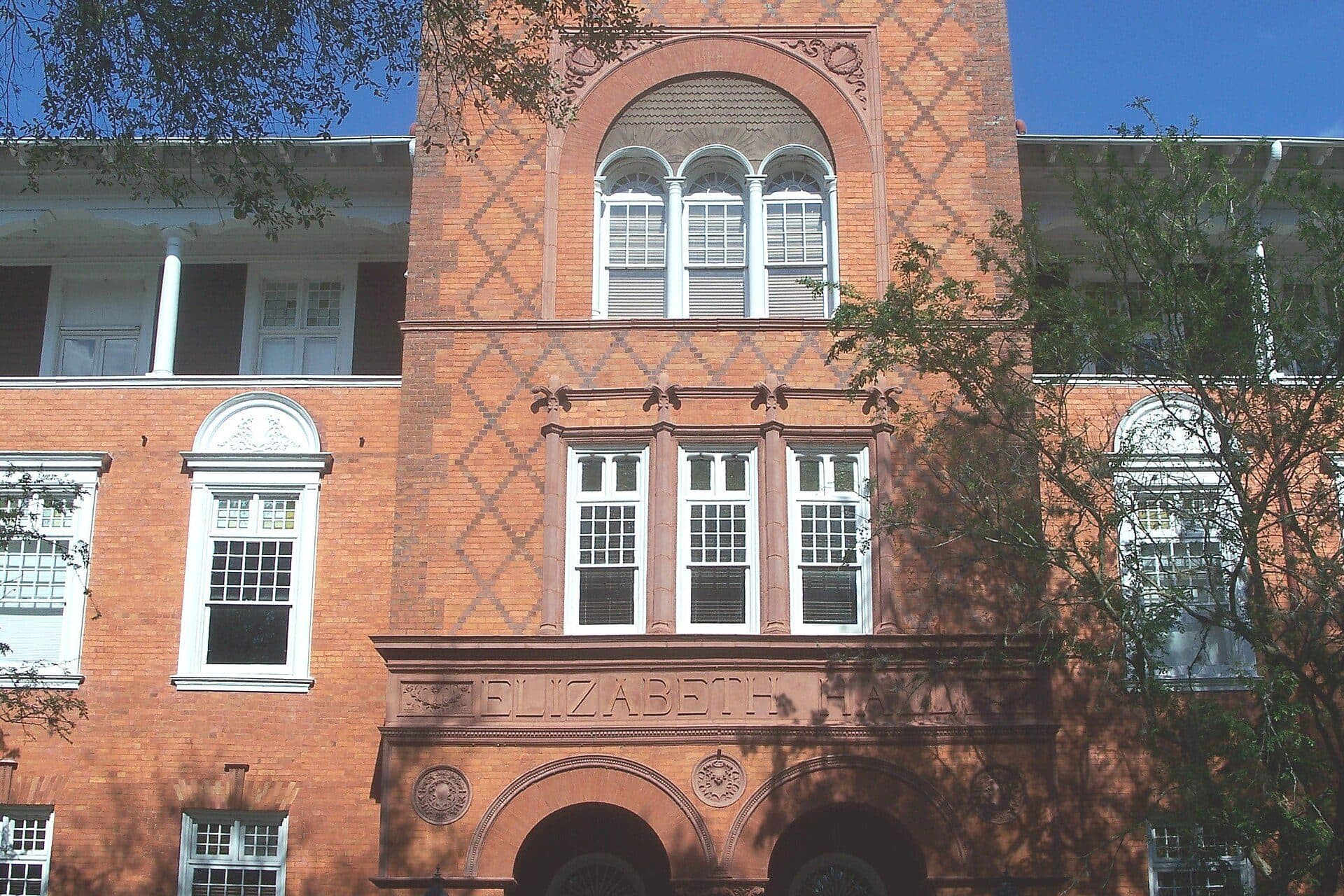 The patterned red-brick tower of Elizabeth Hall at Stetson University, framed by tree branches