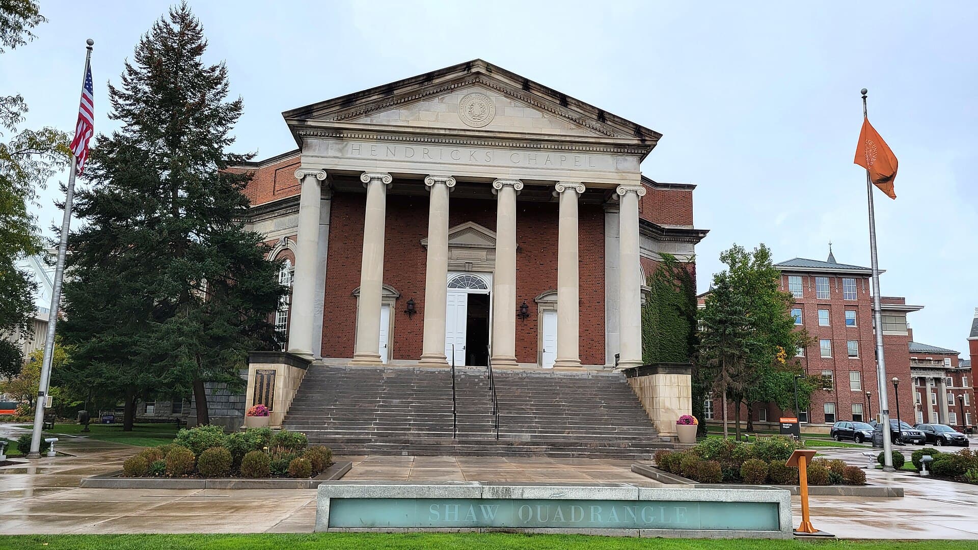 Hendricks Chapel's red-brick front with tall white columns and a domed roof, above wide steps and a fountain, with flags in front