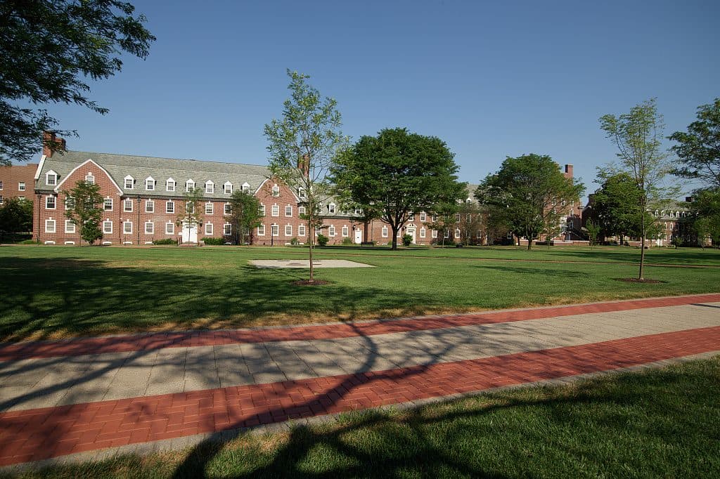 A brick University of Delaware residence hall behind a green lawn and brick path