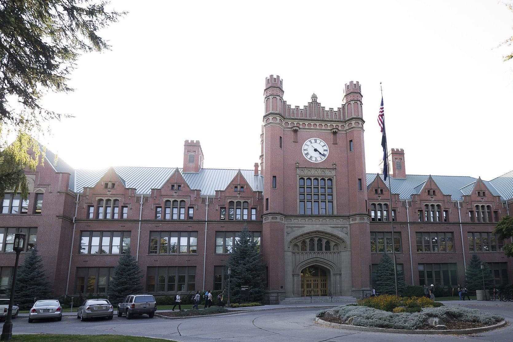The University of Idaho's red-brick Administration Building with its central clock tower and turrets behind a landscaped circle