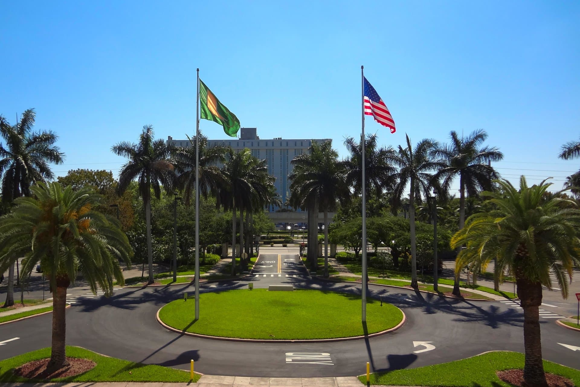 Flagpoles and palm trees around a circular drive at the main entrance to the University of Miami's Coral Gables campus