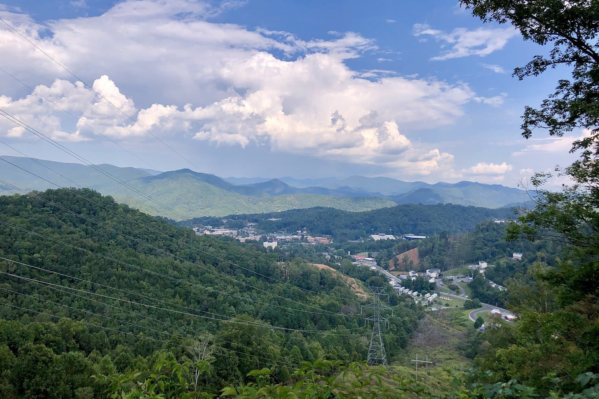 A green mountain valley under big summer clouds, with Western Carolina University campus buildings spread along the valley floor