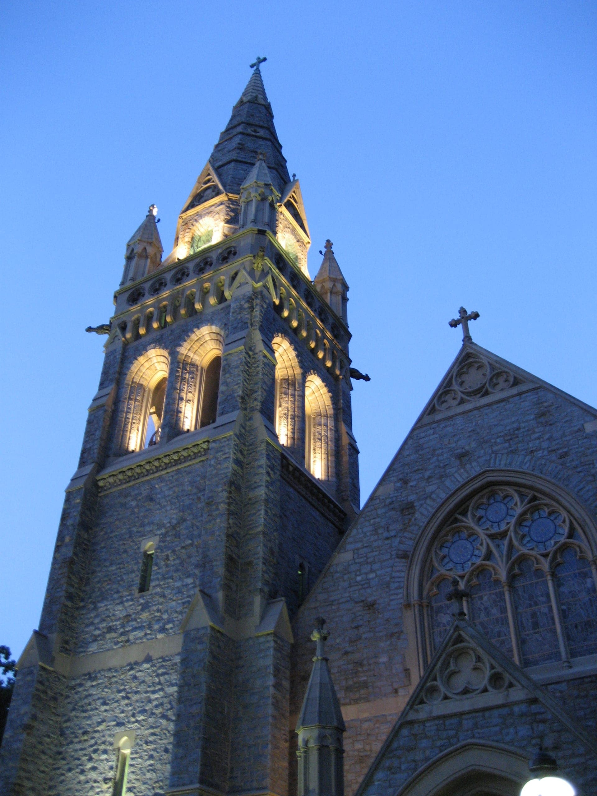 The lit stone tower of Packer Chapel at Lehigh against an evening blue sky