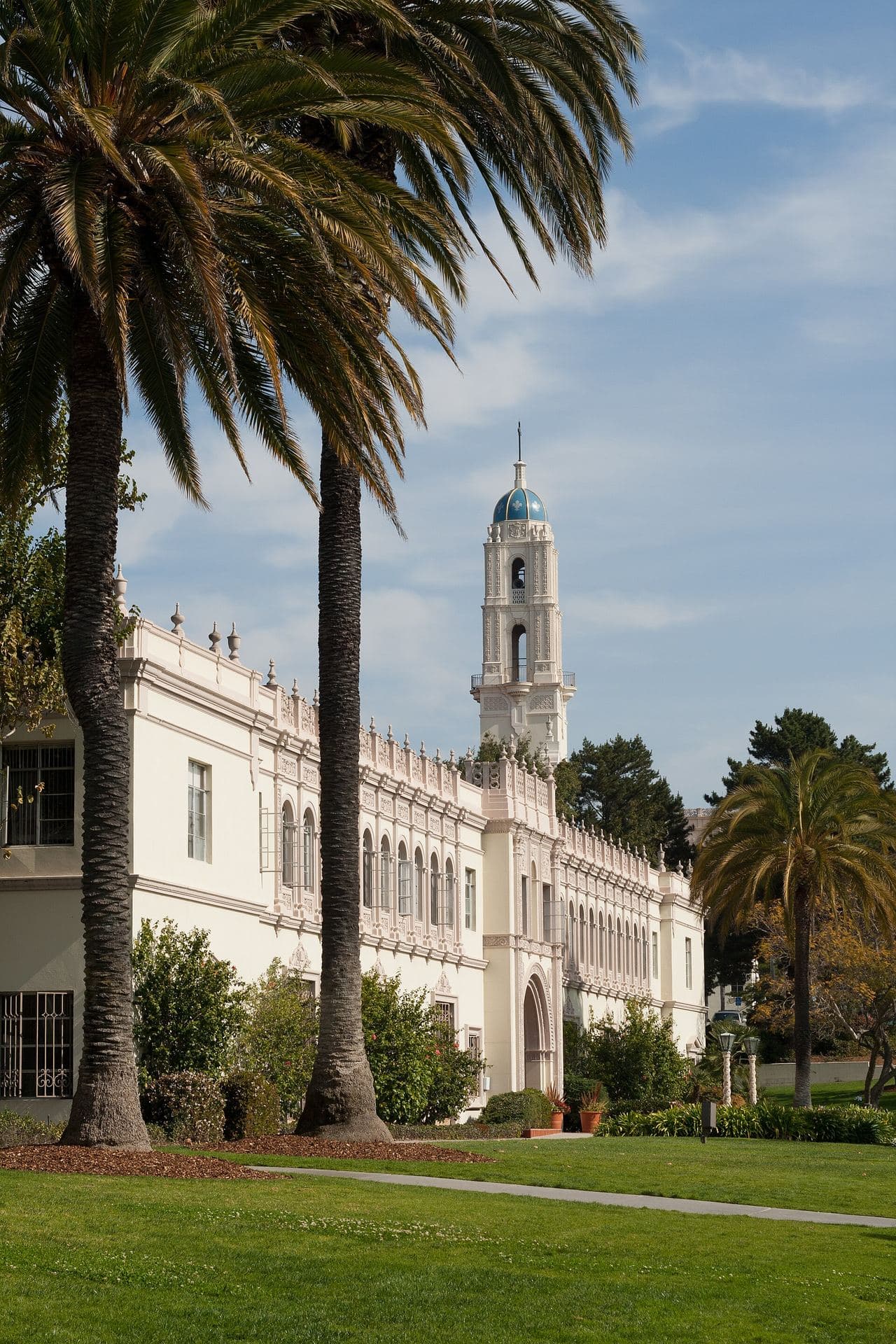 Founders Hall at the University of San Diego with the blue-domed tower of the Immaculata church behind it and palm trees in front