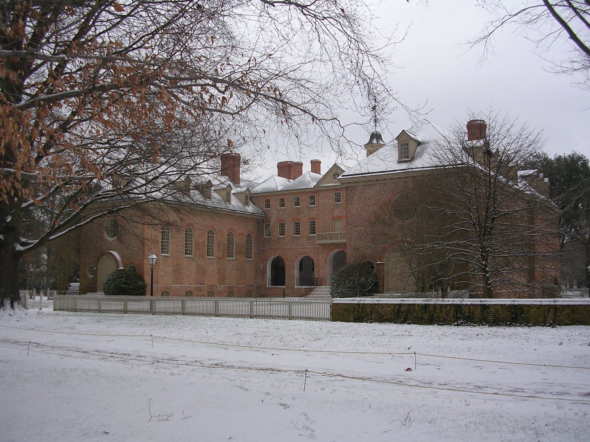The red-brick Wren Building at William & Mary behind a snowy lawn and bare trees